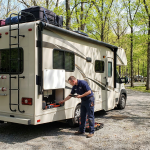Mobile RV technician performing a pre-trip inspection on a Class C motorhome before a vacation.